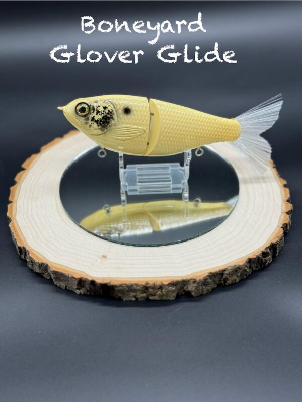 A pale yellow fishing lure with black spots under the title "Boneyard Glover Glide".