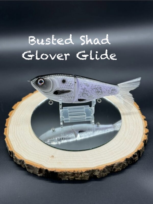 A light purple and black fishing lure under the title "Busted Shad Glover Glide".