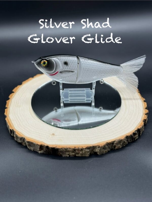 A silver and black fishing lure under the title "Silver Shad Glover Glide".