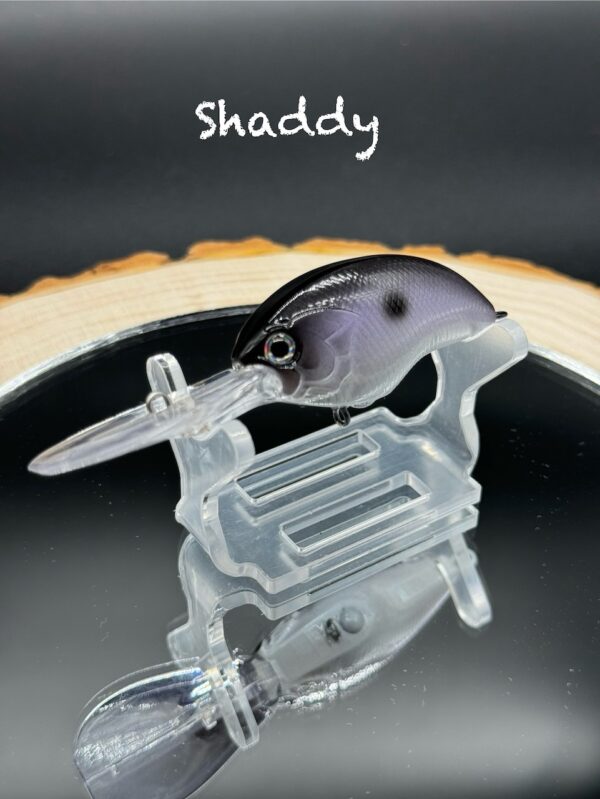 A fishing lure painted black with some subtle purple under the title "Shaddy".