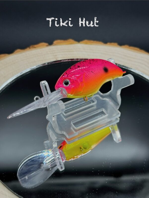 A fishing lure painted a hot pink-orange-yellow gradient with black speckles under the title "Tiki Hut".