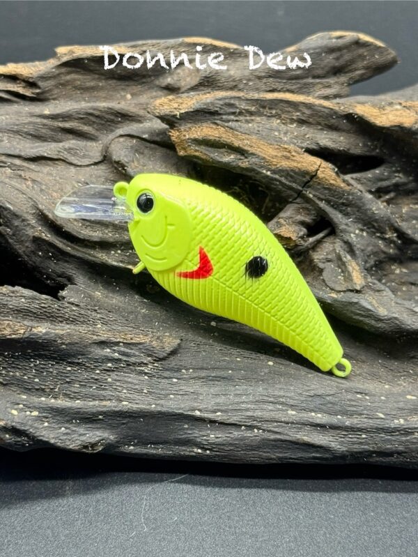 A fishing lure painted bright yellow with a red swoosh shape and black dot on its side.